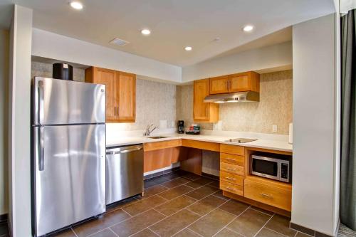 a kitchen with a stainless steel refrigerator and wooden cabinets at Homewood Suites by Hilton Seattle-Issaquah in Issaquah