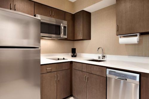a kitchen with wooden cabinets and a stainless steel refrigerator at Homewood Suites By Hilton Irvine John Wayne Airport in Irvine