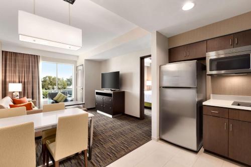 a kitchen and living room with a table and a refrigerator at Homewood Suites By Hilton Irvine John Wayne Airport in Irvine