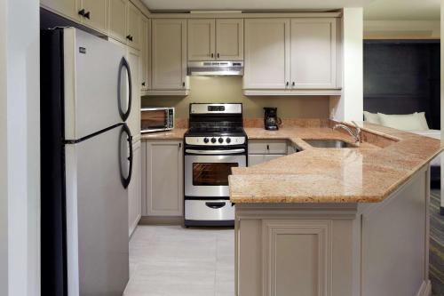 a kitchen with white cabinets and a white refrigerator at Homewood Suites by Hilton Mont-Tremblant Resort in Mont-Tremblant