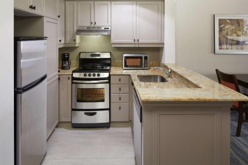 a kitchen with white cabinets and a stove top oven at Homewood Suites by Hilton Mont-Tremblant Resort in Mont-Tremblant