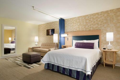 Home2 Suites by Hilton Fort St. John في فورت سانت جون: غرفة فندقية بسرير كبير واريكة