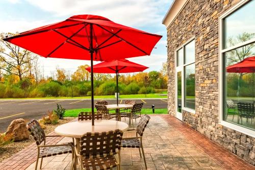 a patio with tables and chairs with red umbrellas at Hampton Inn Lockport - Buffalo, NY in Lockport