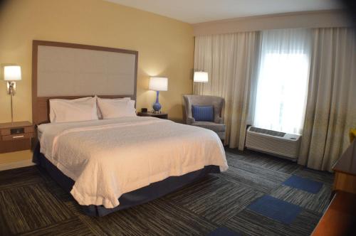 a hotel room with a bed and a chair at Hampton Inn Lockport - Buffalo, NY in Lockport