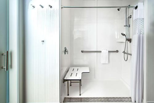 uma casa de banho branca com um chuveiro e um banco em Hampton Inn Lockport - Buffalo, NY em Lockport