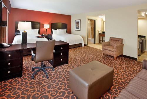 Hampton Inn & Suites Dickinson ND في ديكنسون: غرفة في الفندق مع غرفة نوم مع مكتب وسرير