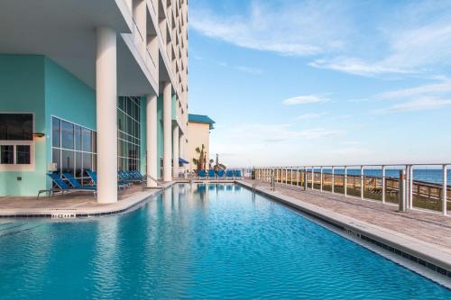 a swimming pool next to a building next to the ocean at Hampton Inn & Suites Panama City Beach-Beachfront in Panama City Beach