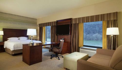 a hotel room with a bed and a desk and a bed and window at Hampton Inn & Suites Pittsburgh Waterfront West Homestead in West Homestead