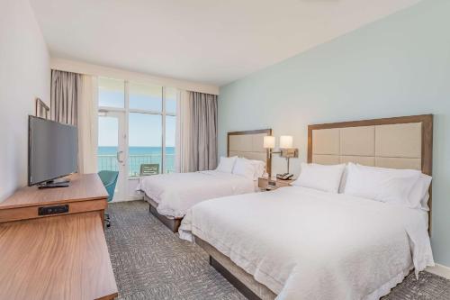 a hotel room with two beds and a flat screen tv at Hampton Inn & Suites Panama City Beach-Beachfront in Panama City Beach