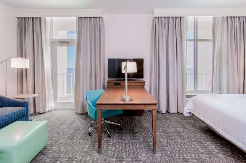 a hotel room with a desk and a bed and a bed and a room with at Hampton Inn & Suites Panama City Beach-Beachfront in Panama City Beach