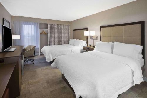 a hotel room with two beds and a flat screen tv at Hampton Inn Toledo-South/Maumee in Maumee