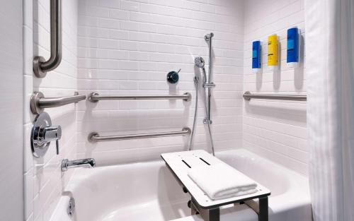 a white bathroom with a bath tub with a bench in it at Tru By Hilton St. George in St. George