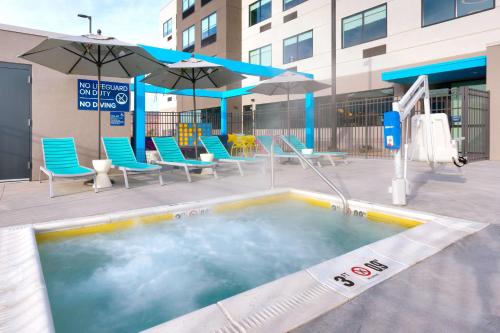 a swimming pool with chairs and umbrellas on a building at Tru By Hilton St. George in St. George