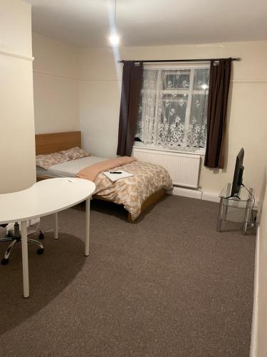 a bedroom with a bed and a desk and a window at Welcome to your new home. in Redbridge