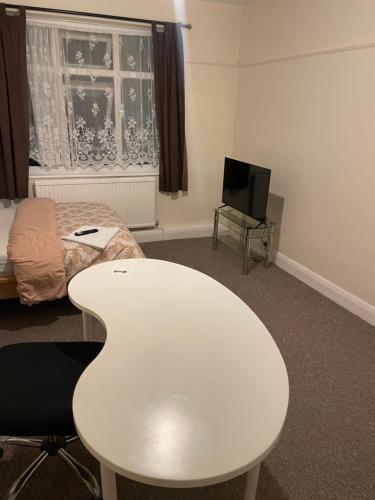 a room with a white table and a bed and a tv at Welcome to your new home. in Redbridge