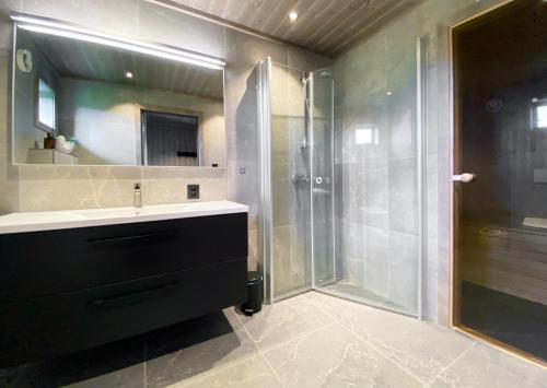 a bathroom with a shower and a sink and a glass shower stall at Sunset Panorama - Superior Cabin Lofoten in Sand