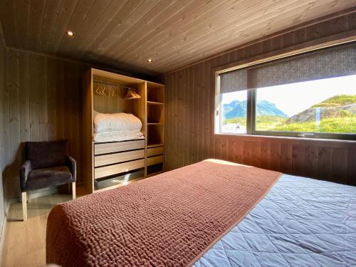 a bedroom with a bed and a window and a chair at Sunset Panorama - Superior Cabin Lofoten in Sand