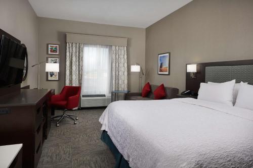 a hotel room with a bed and a flat screen tv at Hampton Inn Bartlesville in Bartlesville