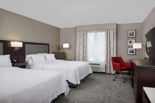 a hotel room with two beds and a red chair at Hampton Inn Bartlesville in Bartlesville