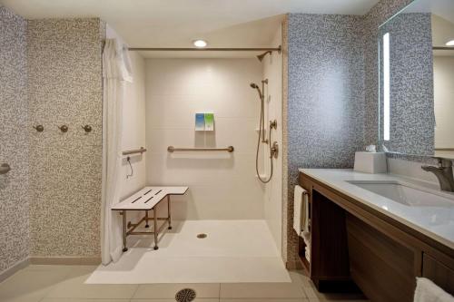 baño con lavamanos, ducha y banco en Home2 Suites By Hilton Amherst Buffalo, en Amherst