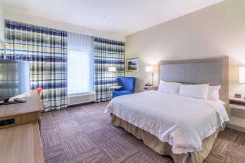 a hotel room with a bed and a blue chair at Hampton Inn Crestview South I-10, Fl in Crestview