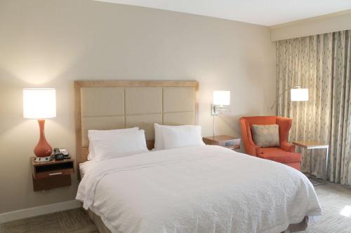 a bedroom with a white bed and a orange chair at Hampton Inn Cape Girardeau I-55 East, MO in Cape Girardeau