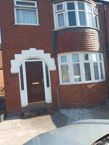 een bakstenen huis met een bruine deur en twee ramen bij Morgan Ease in Manchester