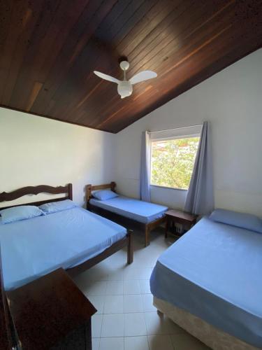 a bedroom with two beds and a ceiling fan at Casa Cantinho de Arembepe - Linda casa com piscina no litoral norte da Bahia in Camaçari