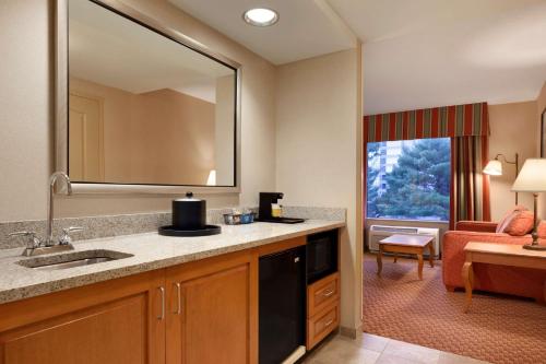 a bathroom with a sink and a living room at Hampton Inn & Suites East Hartford in East Hartford