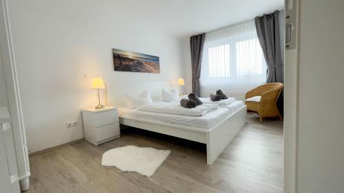ein weißes Schlafzimmer mit einem Bett und einem Fenster in der Unterkunft Strandhaus Nordseebrandung Fewo A1.1 in Cuxhaven