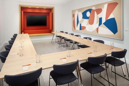 a conference room with tables and chairs and a screen at Canopy By Hilton Grand Rapids Downtown in Grand Rapids
