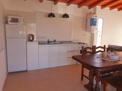 een keuken met een tafel en een witte koelkast bij Complejo familia Yedynak in San Rafael