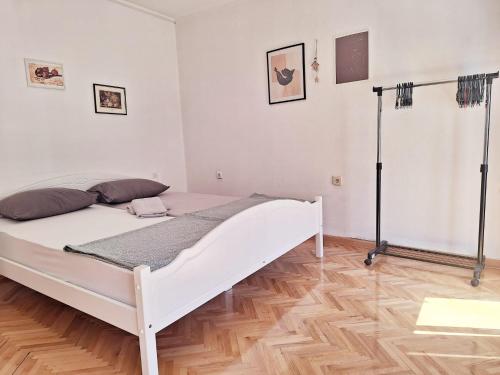 a bedroom with a white bed and a wooden floor at Apartman Square in Mostar