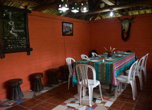 einen Tisch mit weißen Stühlen in einem Zimmer mit orangefarbenen Wänden in der Unterkunft Kawsay- Hospedaje y Alimentacion in Ibarra