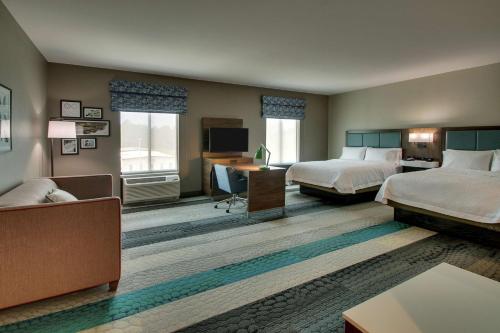 a hotel room with two beds and a desk at Hampton Inn & Suites By Hilton Southport in Southport
