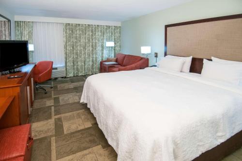 een hotelkamer met een groot bed en een televisie bij Hampton Inn Lafayette Louisiana in Scott