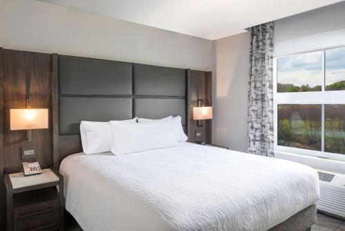 a bedroom with a large bed and a large window at Hilton Garden Inn Hanover Lebanon in Lebanon