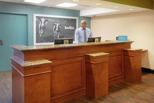 a man is standing behind a reception desk at Hampton Inn & Suites Kansas City-Merriam in Merriam