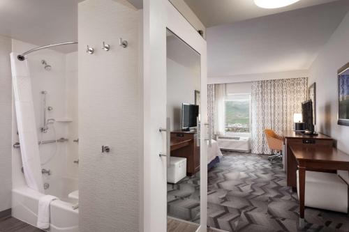 a hotel room with a bathroom with a shower and a desk at Hampton Inn Lewiston, ID in Lewiston