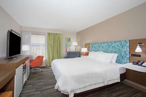 a hotel room with a bed and a flat screen tv at Hampton Inn & Suites Kansas City-Merriam in Merriam