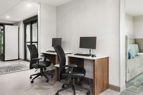 a room with a desk with a computer and two chairs at Hampton Inn Milwaukee Brookfield in Brookfield