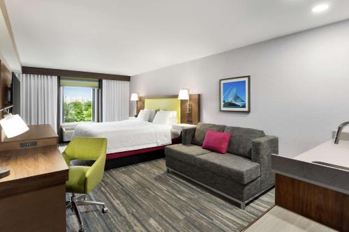 a hotel room with a bed and a couch at Hampton Inn Milwaukee Brookfield in Brookfield