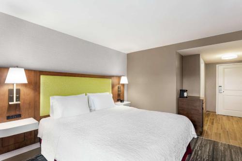 a hotel room with a large bed with white sheets at Hampton Inn Milwaukee Brookfield in Brookfield
