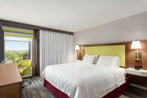 a hotel room with a bed and a large window at Hampton Inn Milwaukee Brookfield in Brookfield