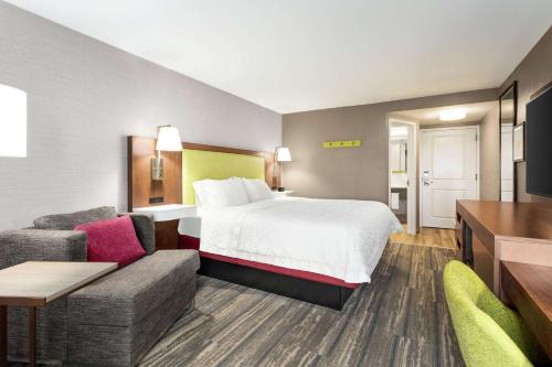 a hotel room with a bed and a couch at Hampton Inn Milwaukee Brookfield in Brookfield