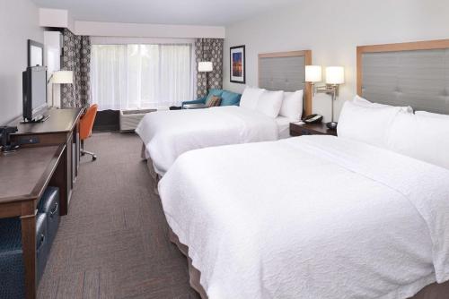 a hotel room with two beds and a flat screen tv at Hampton Inn Portland East in Portland