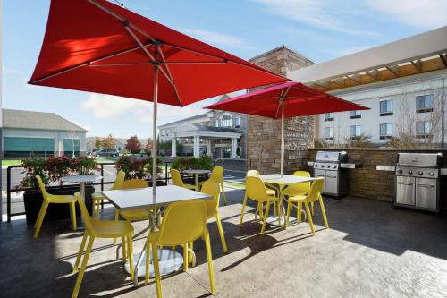 a patio with tables and chairs and red umbrellas at Home2 Suites By Hilton Warminster Horsham in Warminster