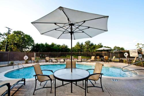 a table and chairs with an umbrella next to a pool at Hampton Inn & Suites Denison in Denison