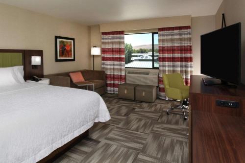 a hotel room with a bed and a flat screen tv at Hampton Inn Richland-Tri Cities in Richland