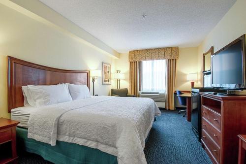 a hotel room with a bed and a flat screen tv at Hampton Inn Pine Grove in Pine Grove